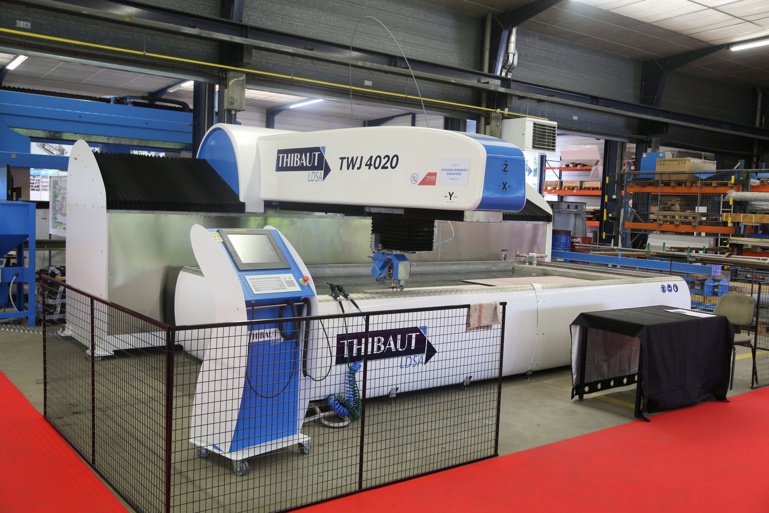 Abrasive waterjet cutting machine with nozzle over a slat table