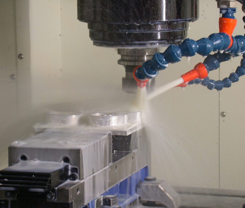 CNC machining centre milling a metal blank under coolant