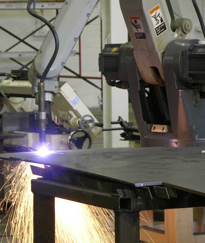 Industrial Motoman robot holding a plasma torch over a metal workpiece