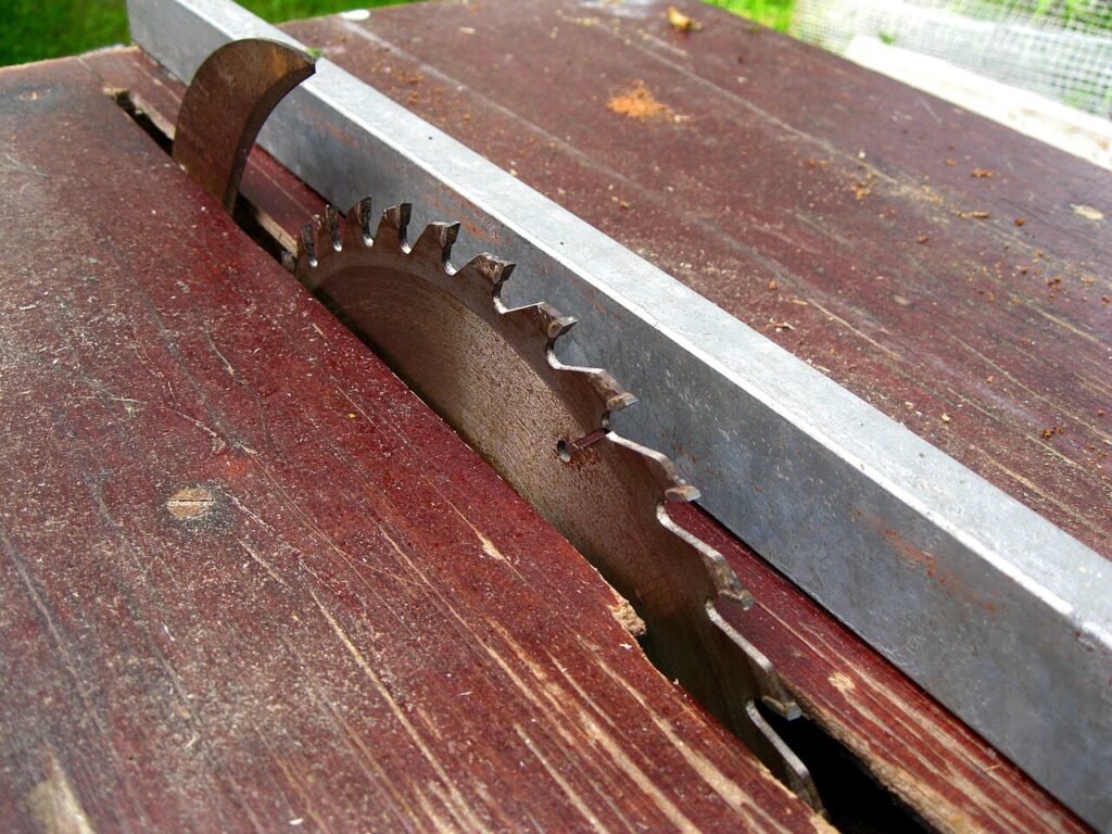 Circular table saw blade standing above a wood table, the toothed rim that removes a slot from wood sheet
